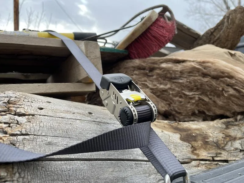 Camping gear and a ratchet strap in a gear-check pile, outdoor equipment brand